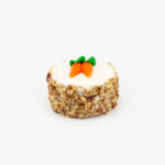 A Single 3" Individual Carrot Cake decorated with Carrots on a light grey background