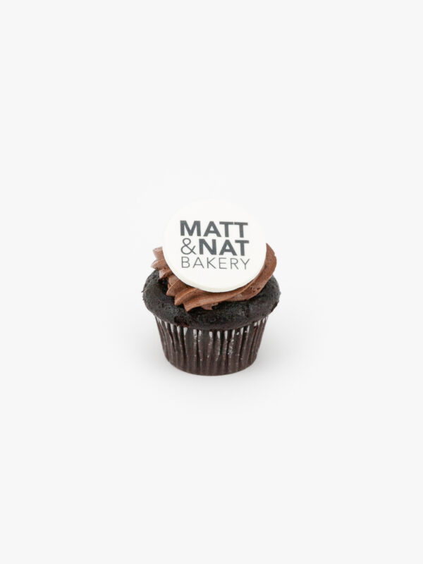 A Round Celebration Logo Disc Topper with a Matt & Nat Bakery Logo on a Chocolate Muffin on a light grey muffin