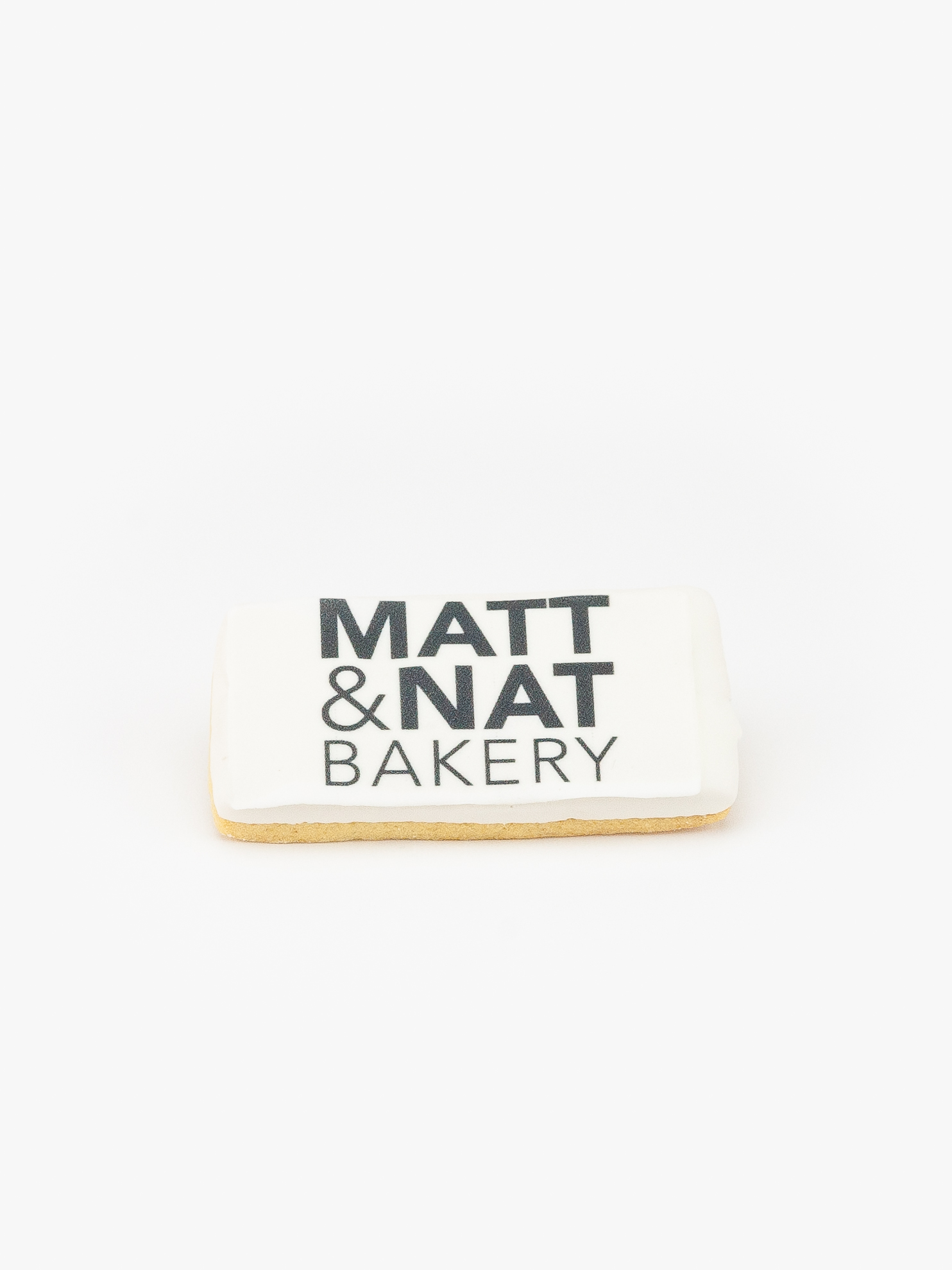 A Rectangular Celebration Logo Cookie with a Matt & Nat Bakery Logo on a light grey background