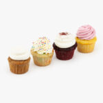 4 Regular Deluxe Assorted Dessert Cupcakes in wrapping on a light grey background