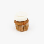 A Single Mini Carrot Dessert Cupcake in wrapping on a light grey background