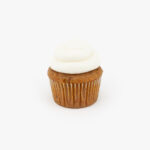 A Single Regular Carrot Dessert Cupcake in wrapping on a light grey background