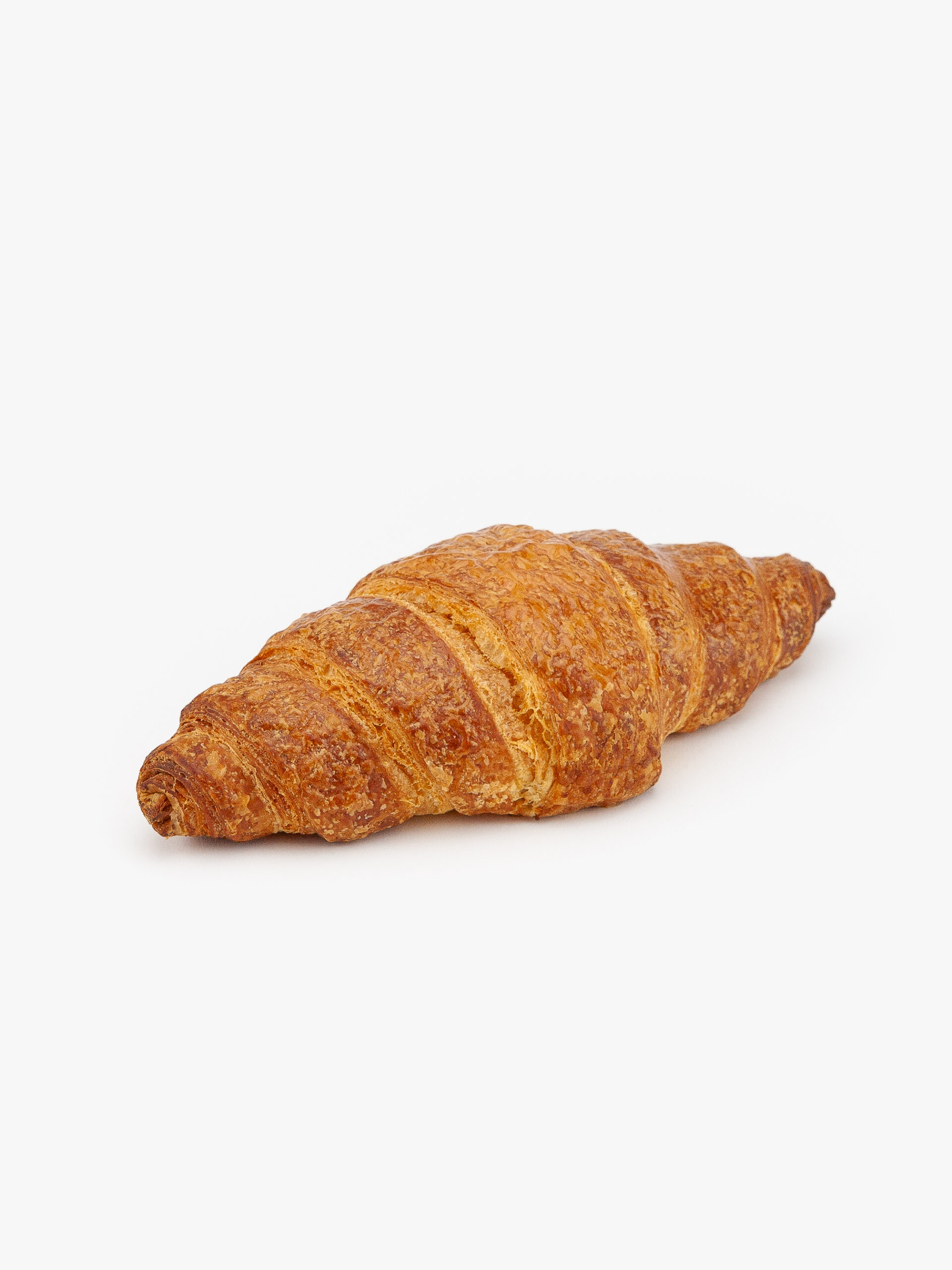 A Single Straight Jumbo Butter Breakfast Croissant on a light grey background