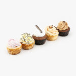 A selection of five 2" Mini Assorted Cheesecakes on a light grey background