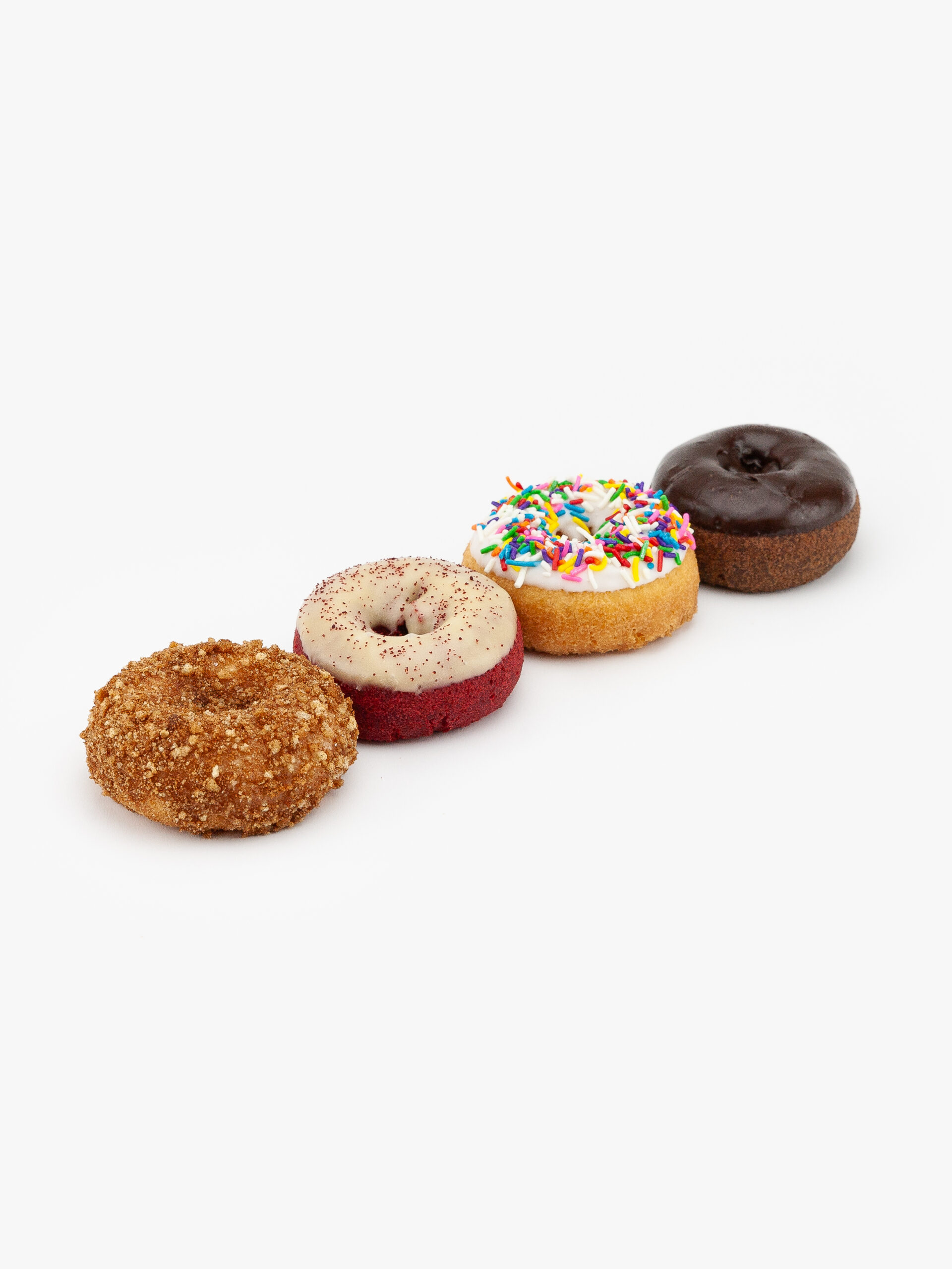 4 Assorted Regular Sprinkle, Red Velvet, Chocolate, Crumb Cake Donut on a light grey background