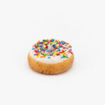 A Regular Sprinkle Cake Donut on a light grey background