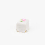 A Single Petit Four Mini Dessert Pastry with a flower decoration on a light grey background