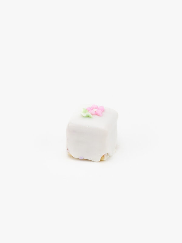 A Single Petit Four Mini Dessert Pastry with a flower decoration on a light grey background