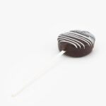 A Single Chocolate Cake Puck Dessert Pastry On a Stick on a light grey background