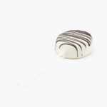 A Single White Cake Puck Dessert Pastry On a Stick on a light grey background