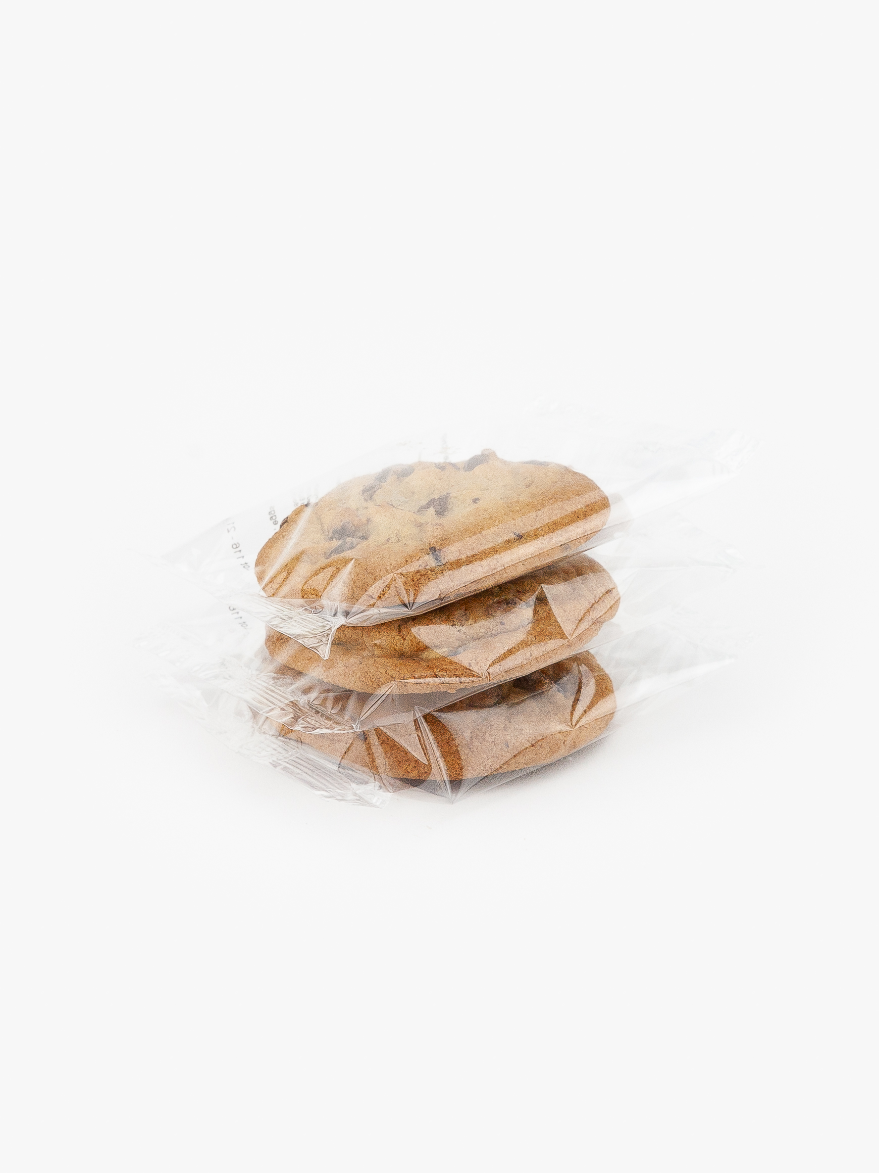 3 Chocolate Chip Cookies Individually Flow Wrapped Stacked on top of each other on a light grey background