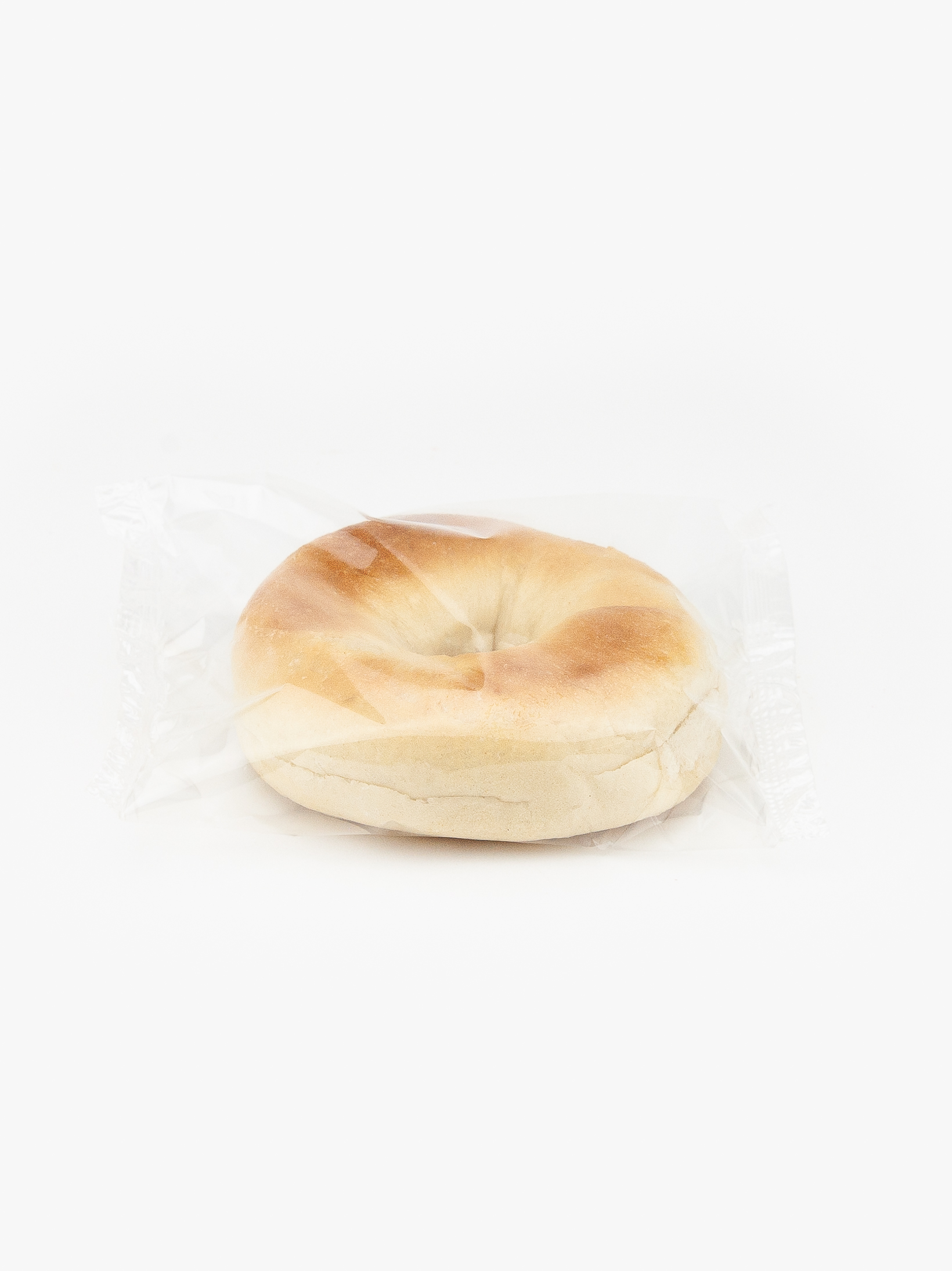 A Single Individual 3 oz. Plain Bagel Wrapped In Plastic on a light grey background