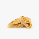 A Jumbo Apple Puff Pastry cut open on a light grey background