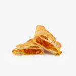 A Jumbo Apricot Puff Pastry cut open on a light grey background