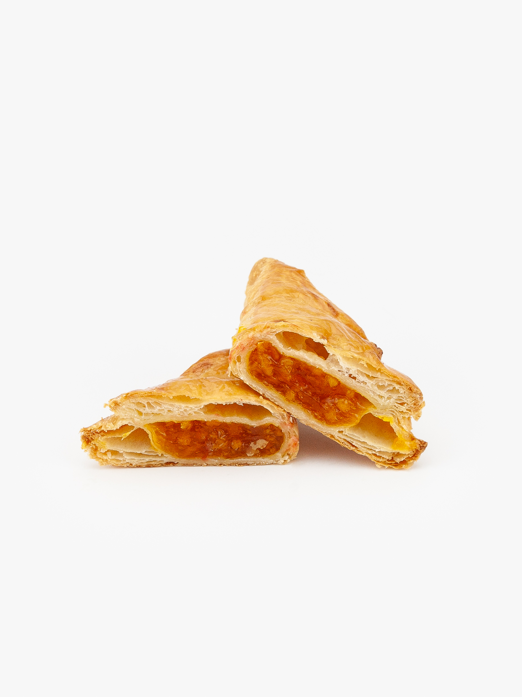 A Jumbo Apricot Puff Pastry cut open on a light grey background