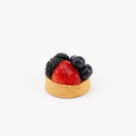 A Fresh Mixed Berry Mini Dessert Tart on light grey background