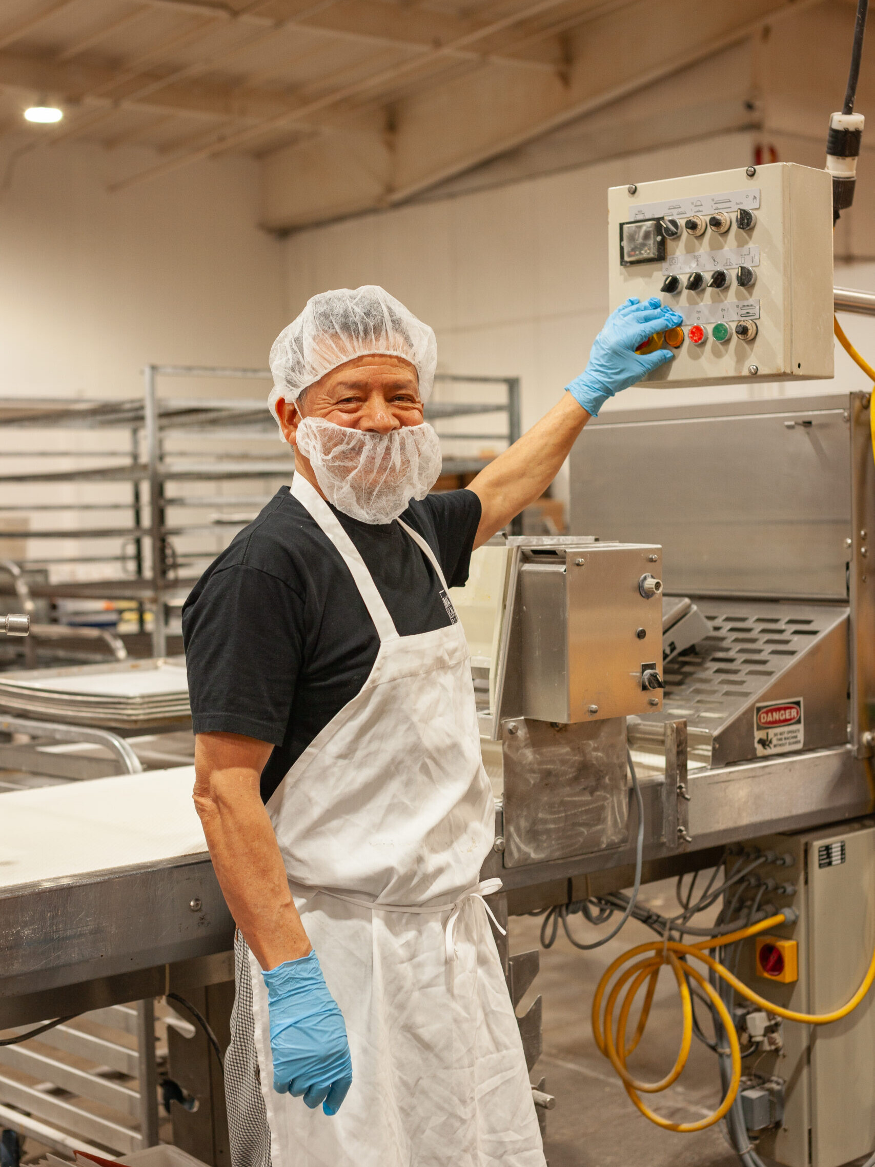 Matt & Nat Bakery Employee operating production machinery while wearing saftey equipment