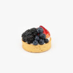 A Fresh Berry Individual Dessert Tart on a light grey background.